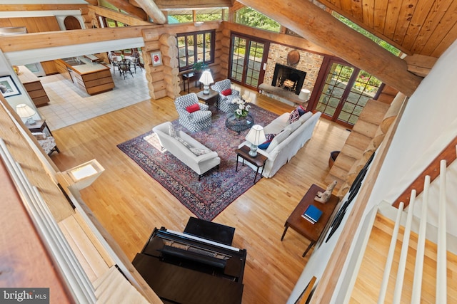 living area featuring wooden ceiling, a stone fireplace, vaulted ceiling with beams, and wood finished floors