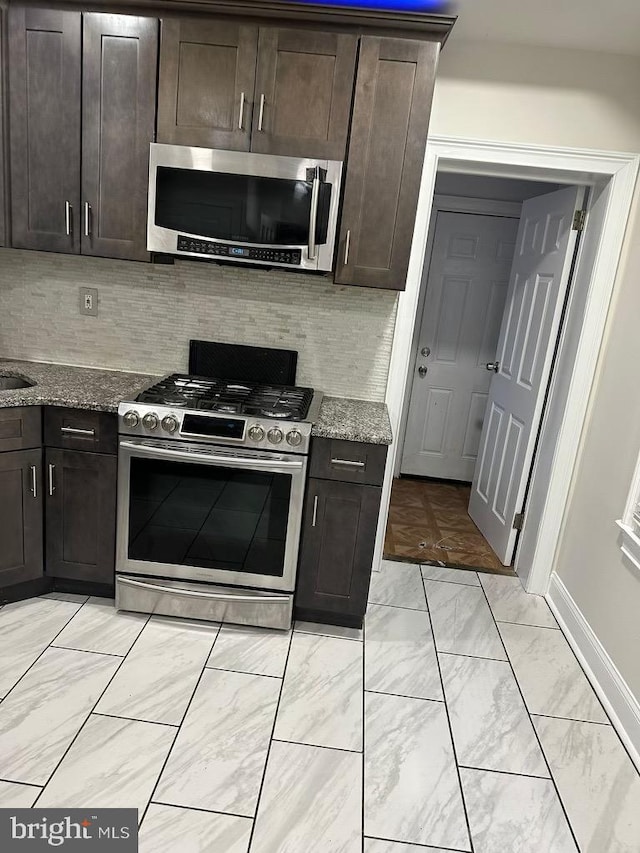 kitchen with stone counters, light tile patterned floors, backsplash, and stainless steel appliances