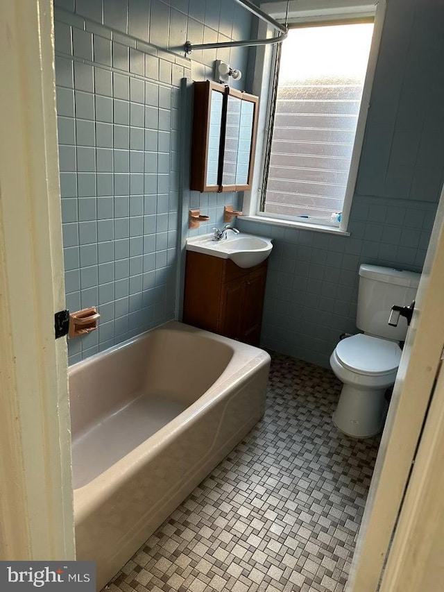 full bathroom featuring tile patterned floors, bathtub / shower combination, vanity, tile walls, and toilet