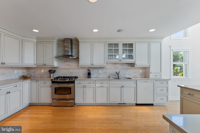 kitchen with sink, backsplash, gas range, wall chimney exhaust hood, and light wood-type flooring