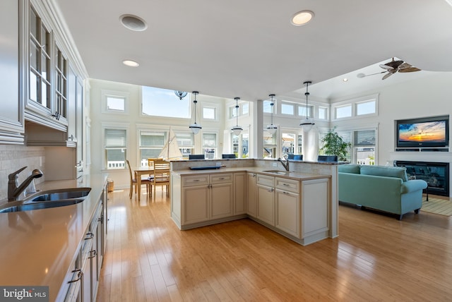 kitchen with sink, a kitchen island with sink, pendant lighting, and light wood-type flooring