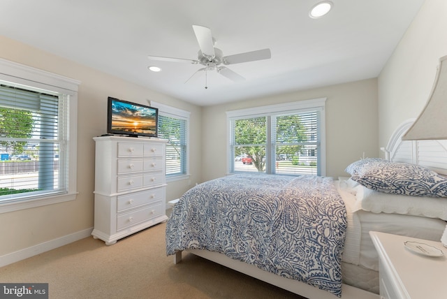 carpeted bedroom featuring multiple windows and ceiling fan