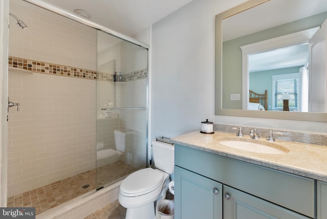 bathroom featuring vanity, toilet, and a shower with shower door