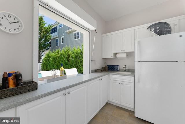 kitchen with white fridge, sink, and white cabinets