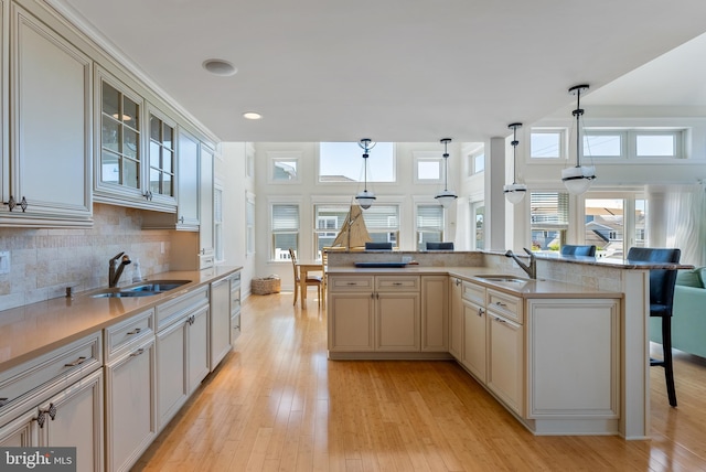 kitchen with hanging light fixtures, decorative backsplash, a breakfast bar area, and sink