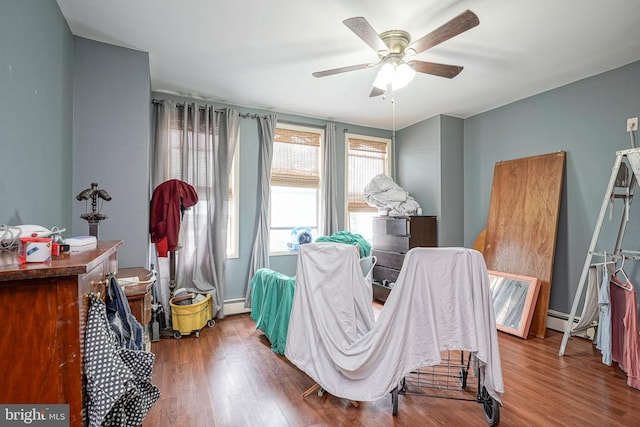 bedroom with ceiling fan, wood-type flooring, and baseboard heating