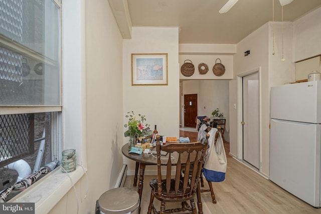 dining space featuring light hardwood / wood-style flooring, ceiling fan, and a baseboard heating unit