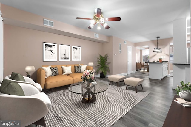 living area featuring a ceiling fan, baseboards, visible vents, and dark wood-style flooring