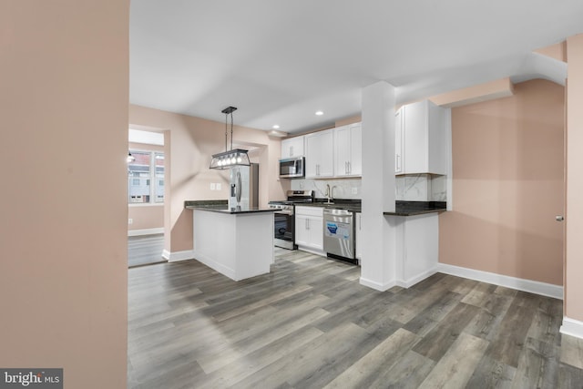 kitchen featuring stainless steel appliances, dark countertops, pendant lighting, and white cabinets