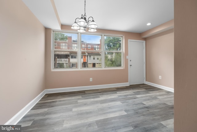 unfurnished dining area with recessed lighting, an inviting chandelier, light wood-style flooring, and baseboards