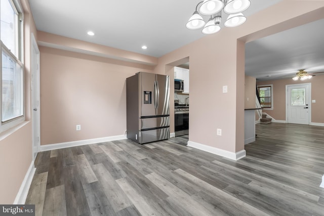 kitchen with appliances with stainless steel finishes, white cabinetry, baseboards, and wood finished floors