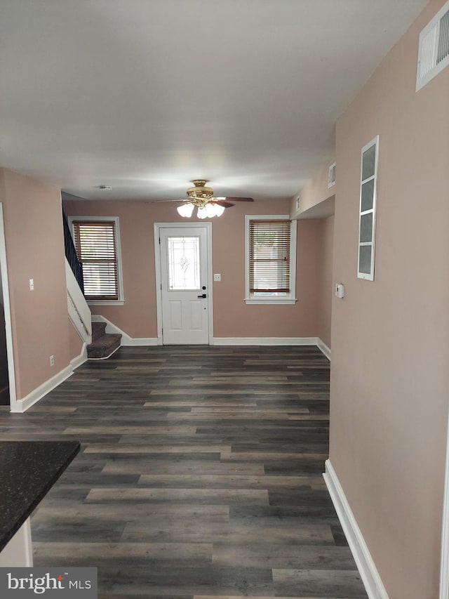 foyer entrance with dark wood-style flooring, visible vents, and baseboards