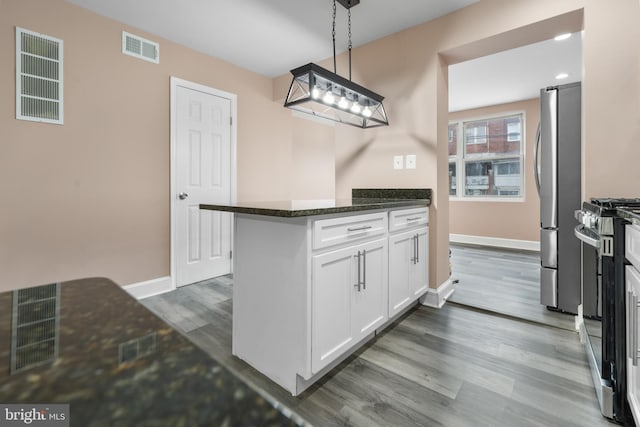 kitchen with stainless steel appliances, white cabinetry, dark hardwood / wood-style floors, pendant lighting, and dark stone countertops