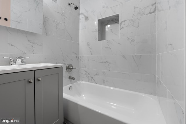 bathroom featuring tile walls, tiled shower / bath combo, and vanity