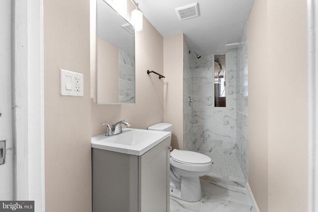 bathroom featuring tile patterned floors, toilet, a tile shower, and vanity