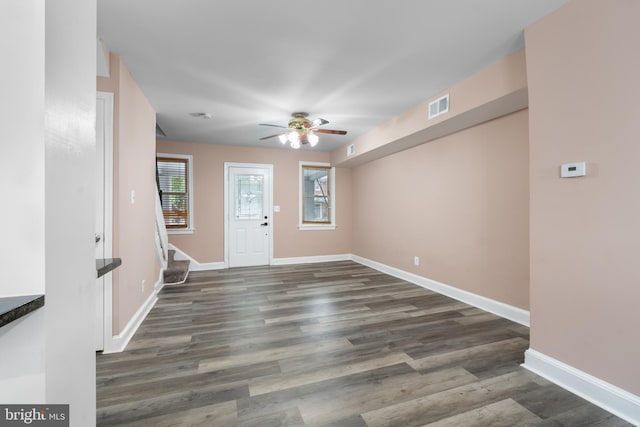 foyer entrance featuring dark wood-style floors, baseboards, and stairs