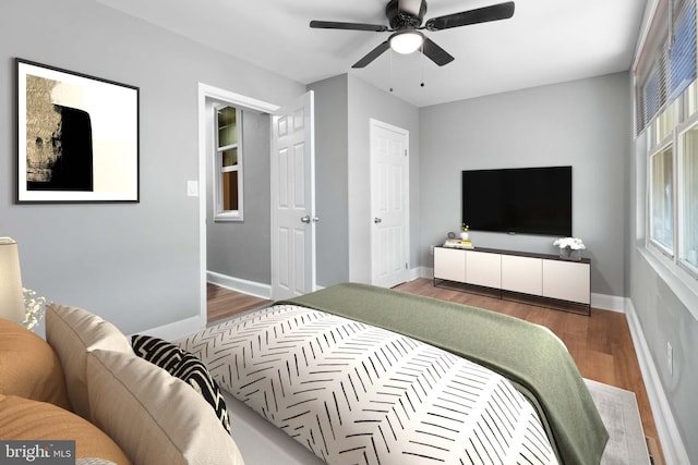 bedroom with dark wood-style floors, a ceiling fan, and baseboards