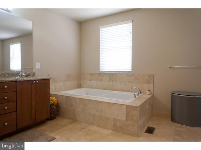 bathroom featuring a relaxing tiled tub, tile patterned flooring, and vanity