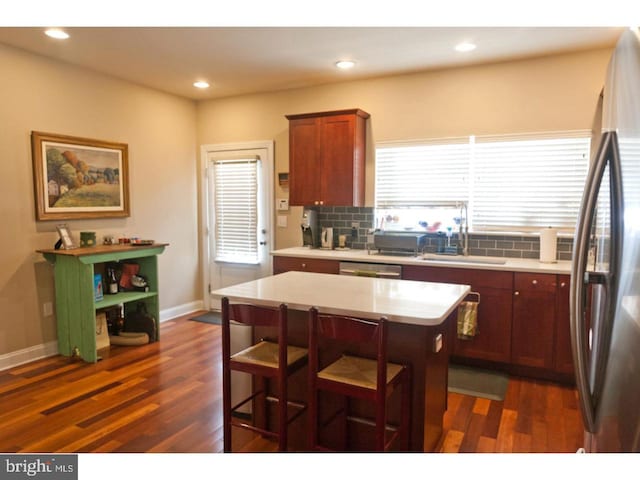 kitchen with stainless steel appliances, decorative backsplash, sink, dark hardwood / wood-style flooring, and a kitchen island