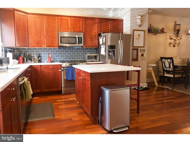 kitchen featuring appliances with stainless steel finishes, a center island, dark hardwood / wood-style floors, and tasteful backsplash