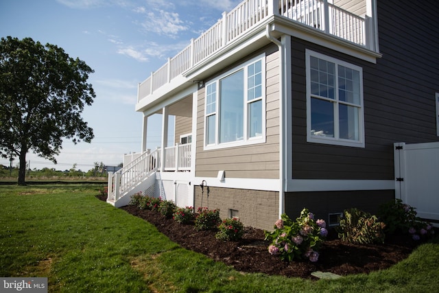 view of side of home featuring a balcony and a lawn