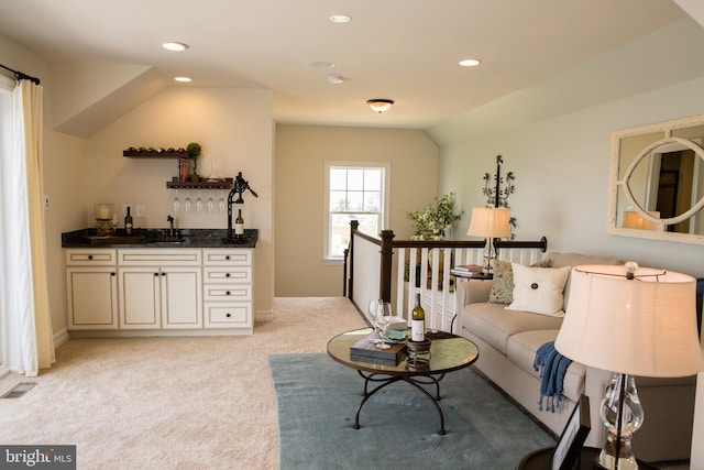 living room with sink, lofted ceiling, and light colored carpet