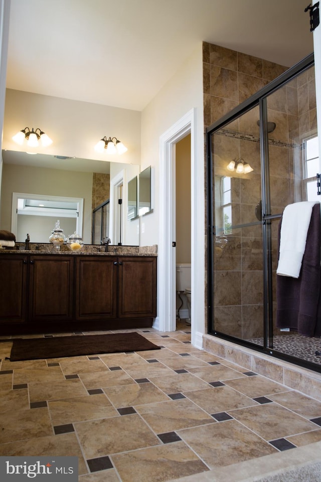 bathroom with toilet, vanity, and a shower with shower door