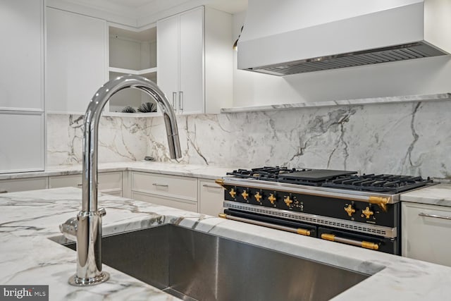 kitchen with high end stainless steel range, white cabinets, backsplash, and custom range hood