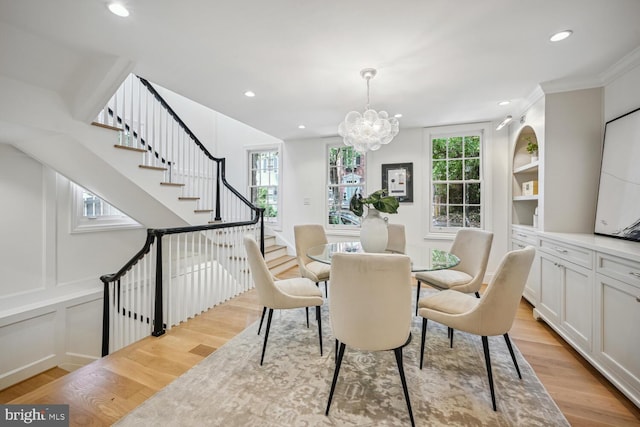 dining space featuring a notable chandelier, light wood-type flooring, ornamental molding, and a wealth of natural light