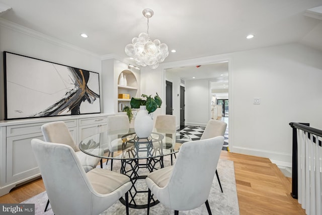 dining room with a notable chandelier, light wood-type flooring, and crown molding