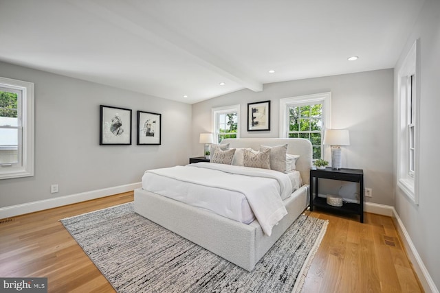 bedroom featuring multiple windows, wood-type flooring, and vaulted ceiling with beams