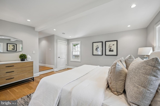 bedroom featuring light wood-type flooring and beam ceiling