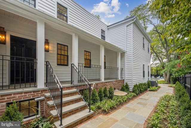 entrance to property with a porch and central AC unit