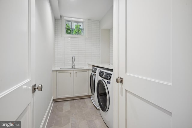 washroom featuring cabinets, washing machine and dryer, and sink