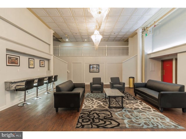 living room featuring a notable chandelier, dark wood-type flooring, and a towering ceiling