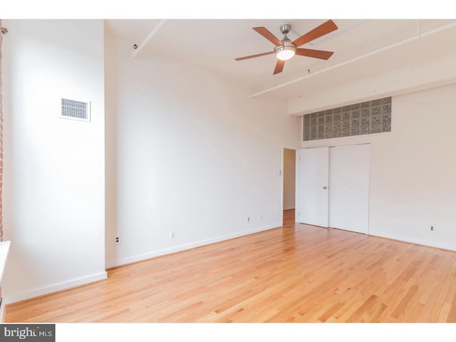 unfurnished room featuring ceiling fan, a high ceiling, and light hardwood / wood-style flooring