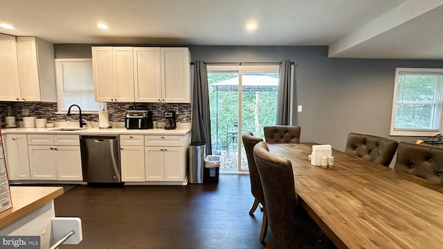 kitchen with sink, dark wood-type flooring, decorative backsplash, stainless steel dishwasher, and white cabinetry