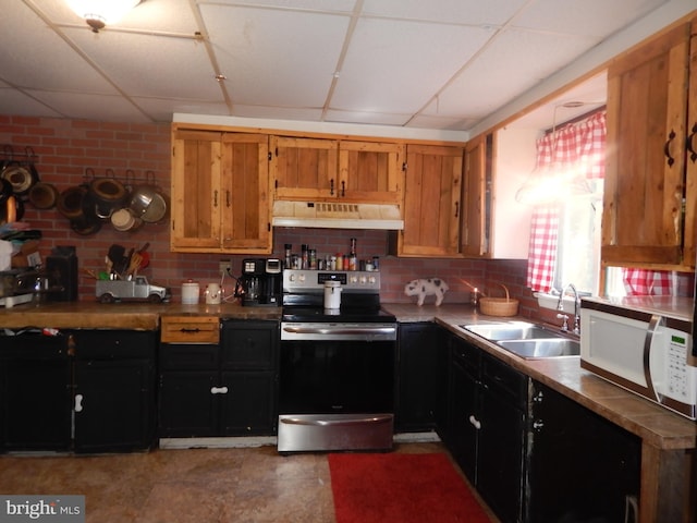 kitchen with stainless steel electric range oven, brick wall, a drop ceiling, and sink