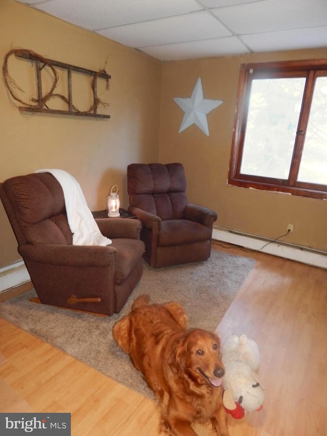 living room featuring a baseboard heating unit, hardwood / wood-style flooring, and a drop ceiling