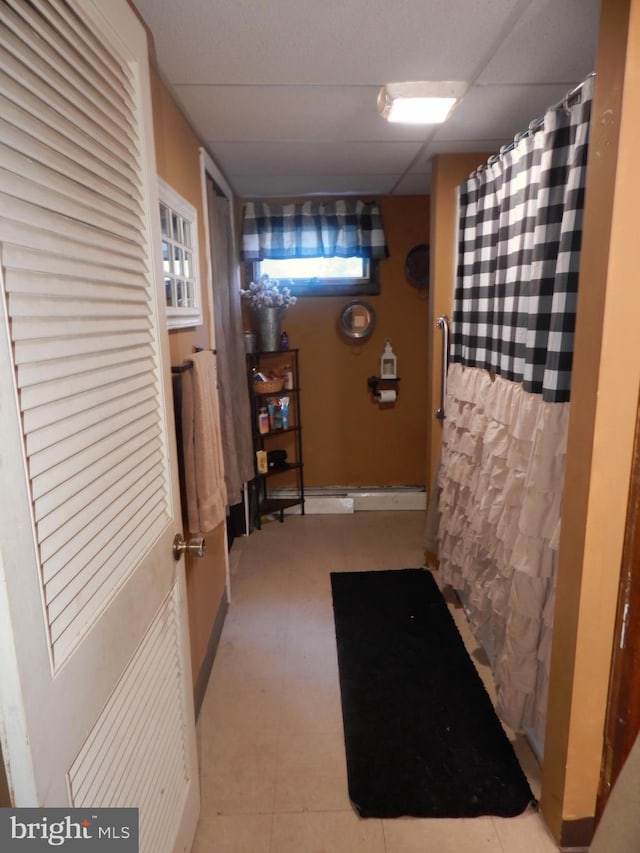 hall featuring light tile patterned floors and a drop ceiling