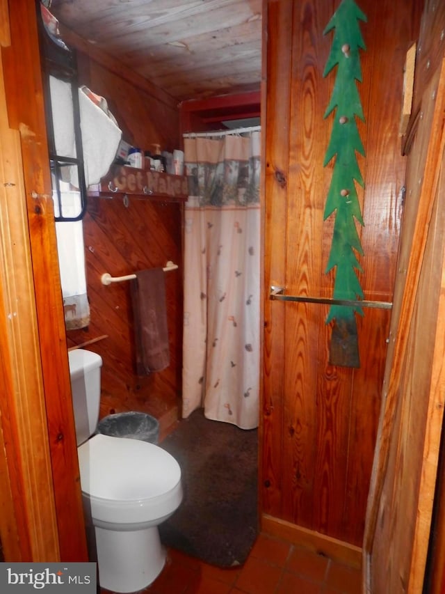 bathroom with tile patterned floors, wood walls, toilet, and wooden ceiling