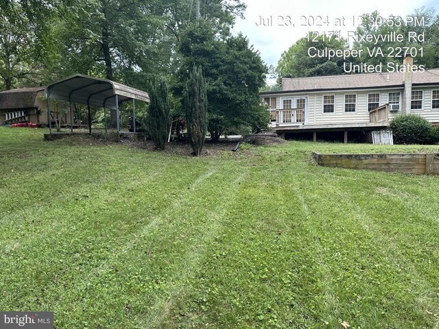 view of yard with a carport and a deck