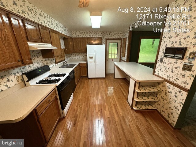 kitchen featuring gas range, white refrigerator with ice dispenser, sink, and light hardwood / wood-style floors