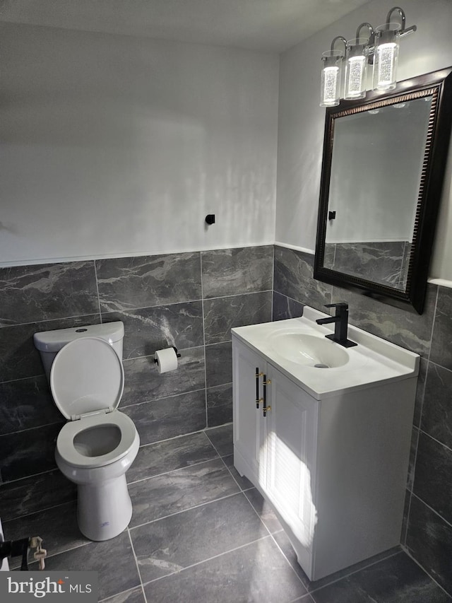 bathroom featuring vanity, tile walls, and toilet