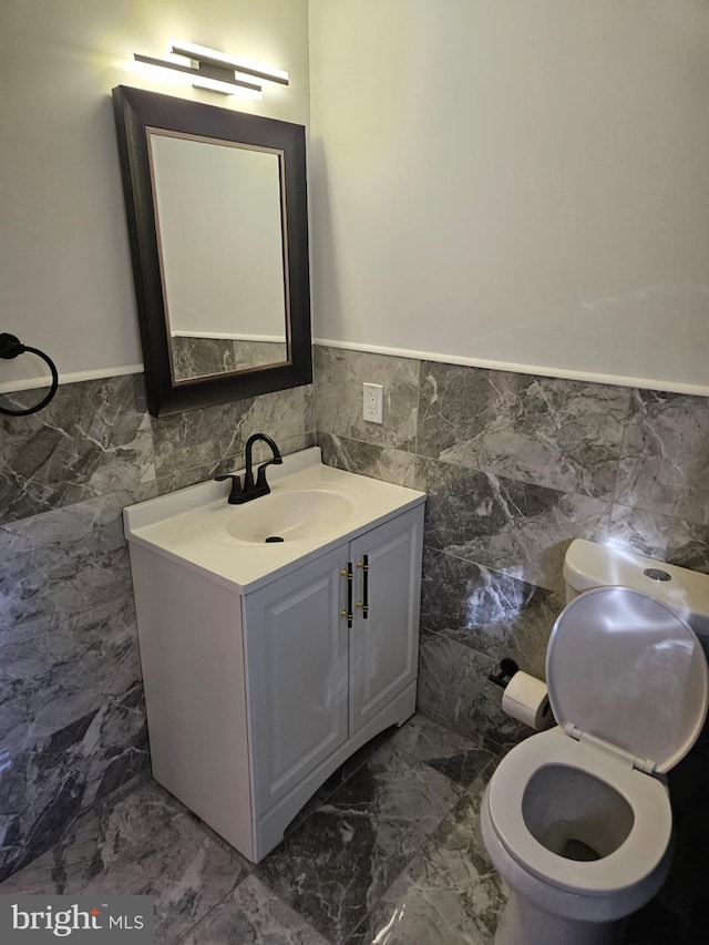 bathroom with vanity, tile walls, and toilet