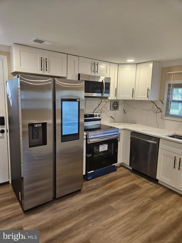 kitchen with tasteful backsplash, dark hardwood / wood-style floors, white cabinets, and appliances with stainless steel finishes