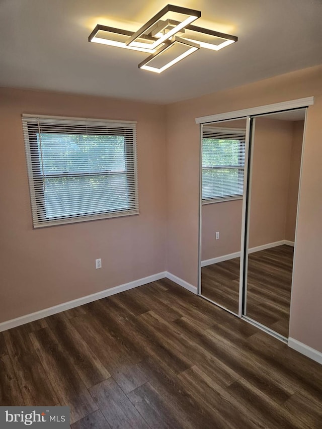 unfurnished bedroom with dark hardwood / wood-style floors and a closet