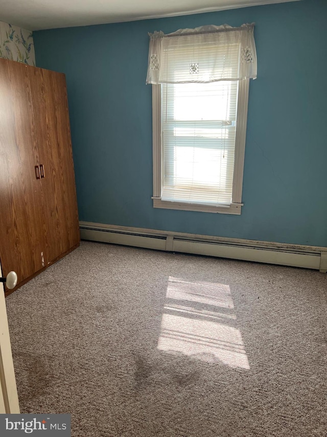 carpeted empty room with a baseboard radiator