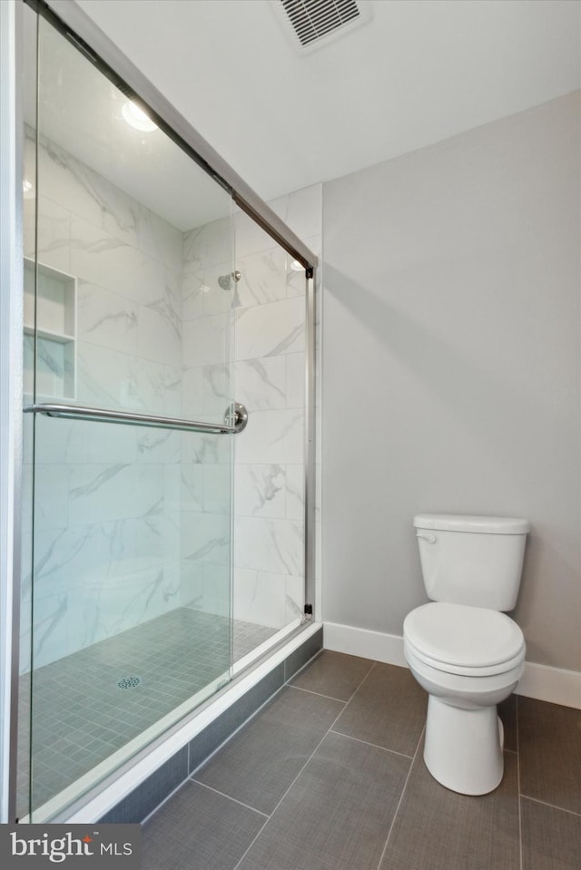 bathroom with tile patterned floors, toilet, and an enclosed shower