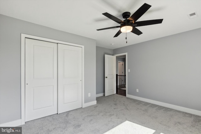 unfurnished bedroom with ceiling fan, a closet, and light carpet